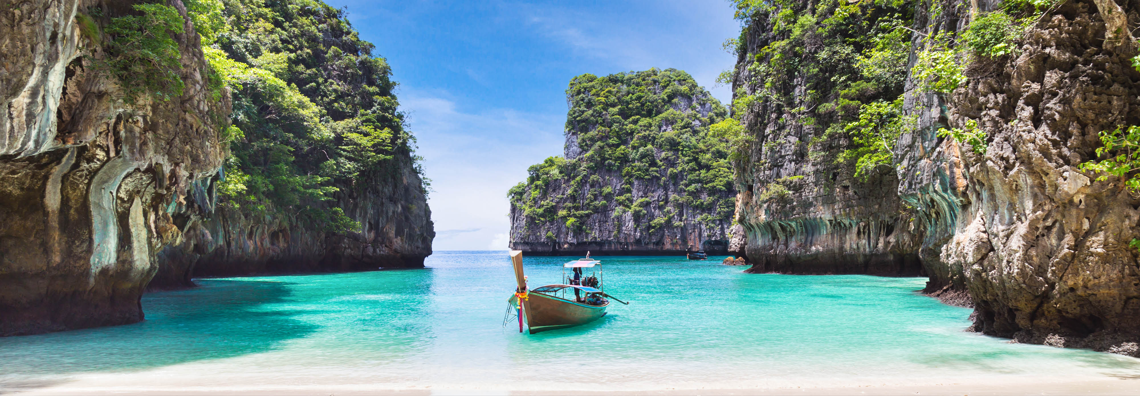 A boat is moored in calm water beside a rocky beach in Asia