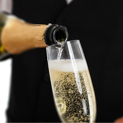 A bottle of champagne being poured into a champagne flute glass