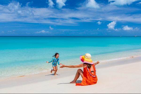 Woman and child playing together on a sunny beach with turquoise water