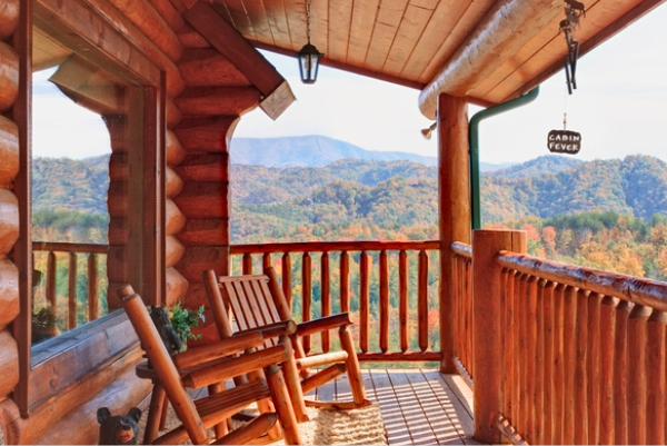 Wooden porch with rocking chairs facing colorful fall mountains