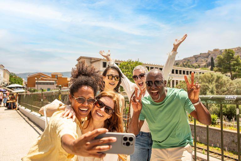 Travelers smiling and taking a group selfie while exploring a sunny destination on a guided Trafalgar vacation.