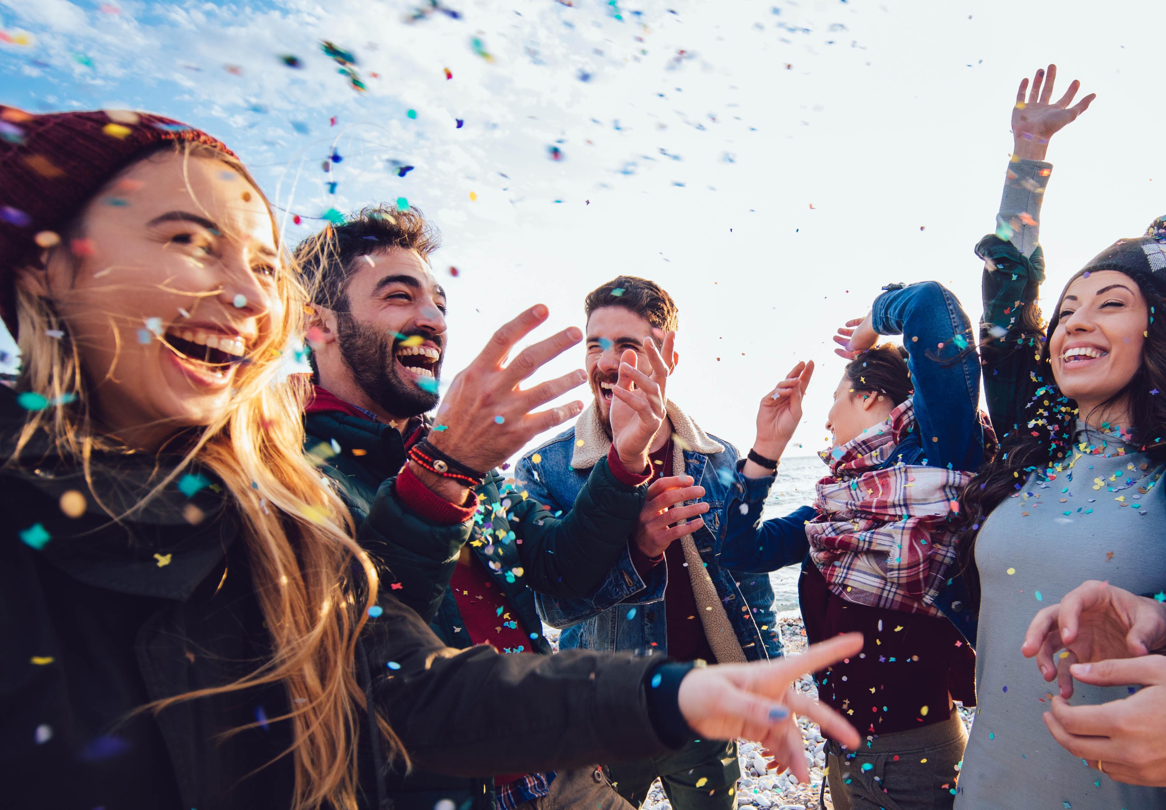 A group of people share celebratory smiles with confetti floating around them