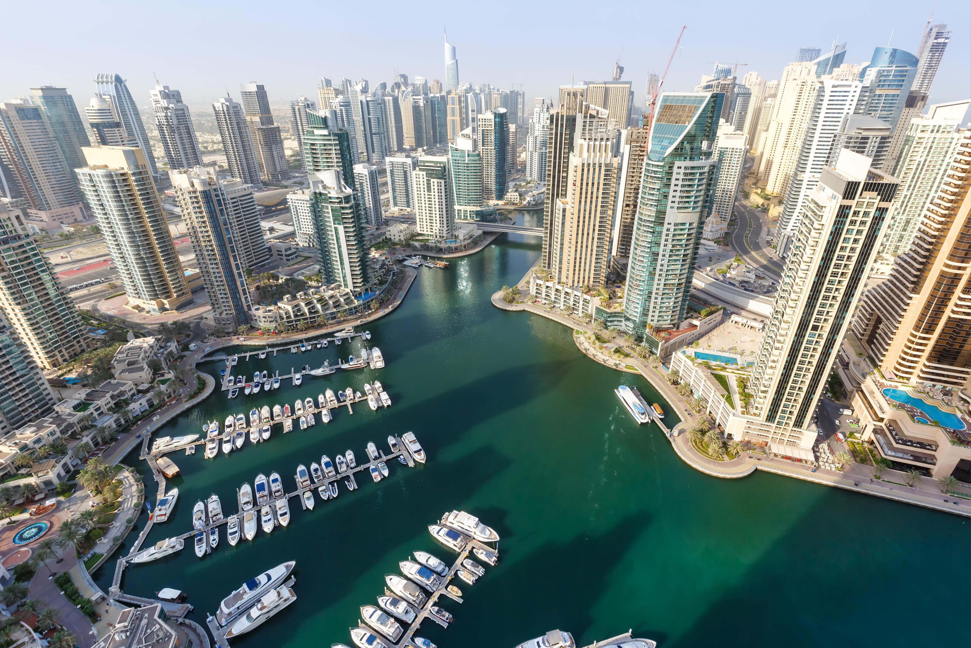 A panoramic view from the top of Dubai Marina, showcasing skyscrapers, yachts, and the vibrant waterfront
