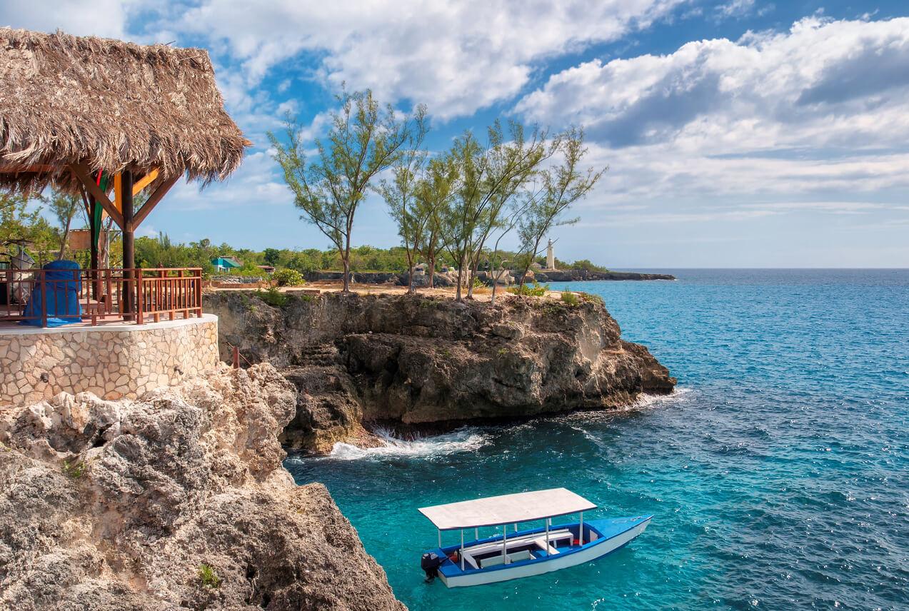 A small boat near a cliff and turquoise waters in Negril, Jamaica