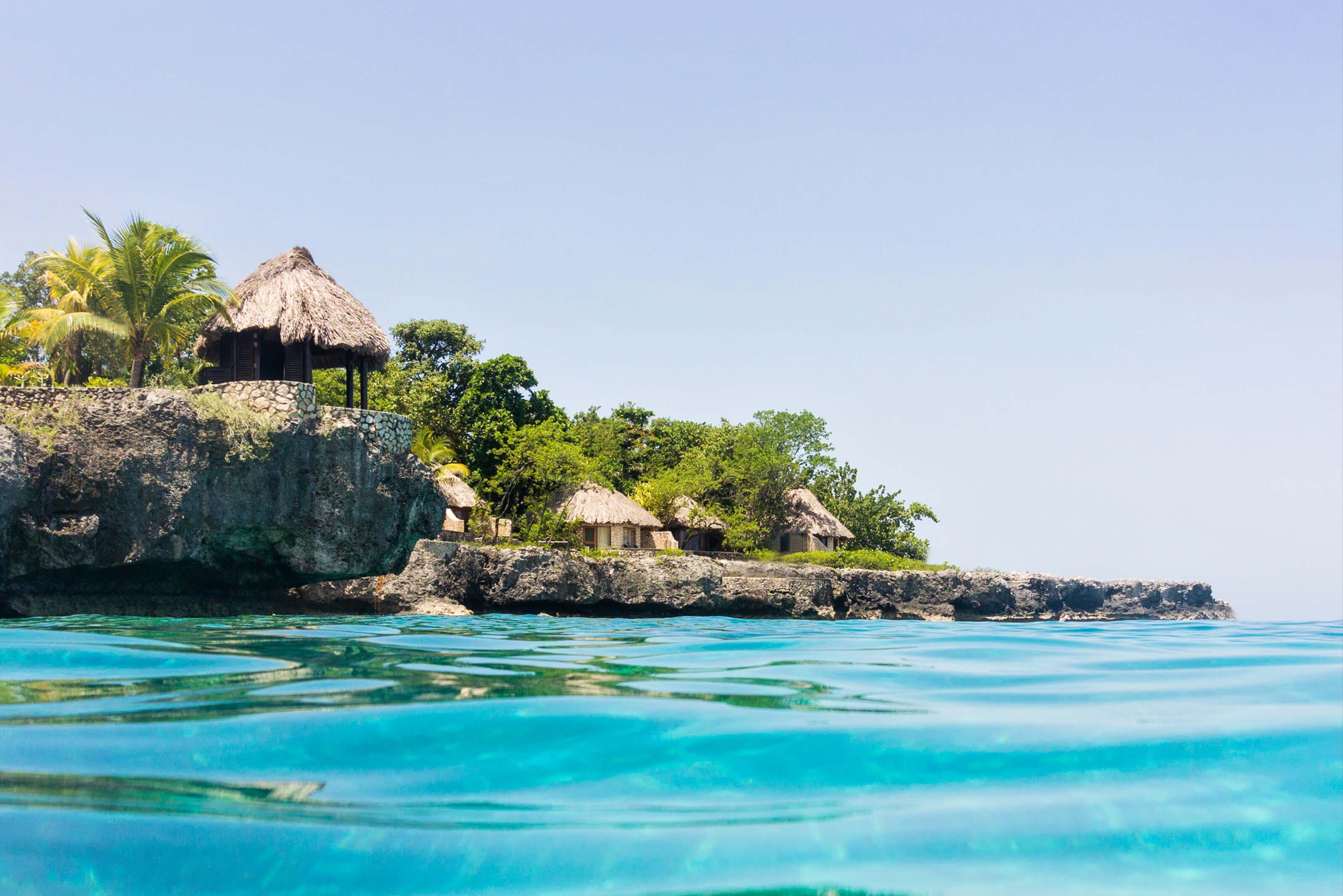 Traditional thatched huts nestled among lush greenery in Negril, Jamaica