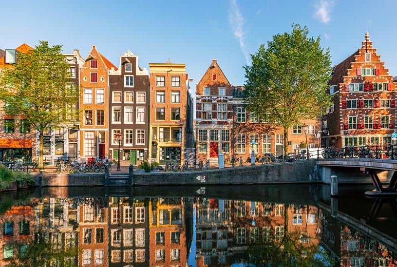 A picturesque canal in the Netherlands featuring a bridge, with various buildings lining the background