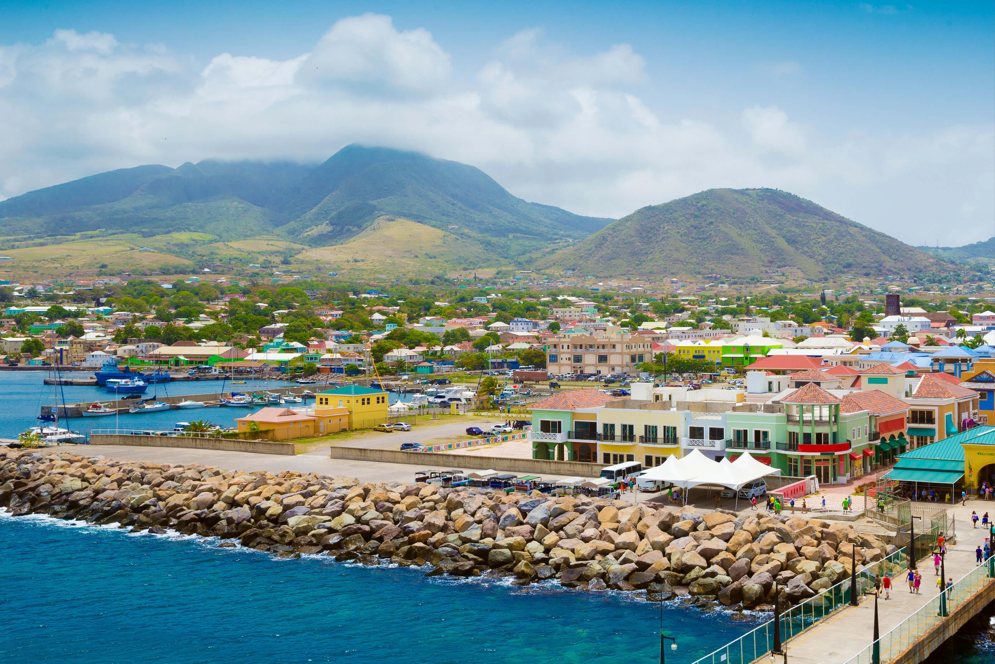Colorful town along the water with lush mountains in the distance on St. Kitts & Nevis