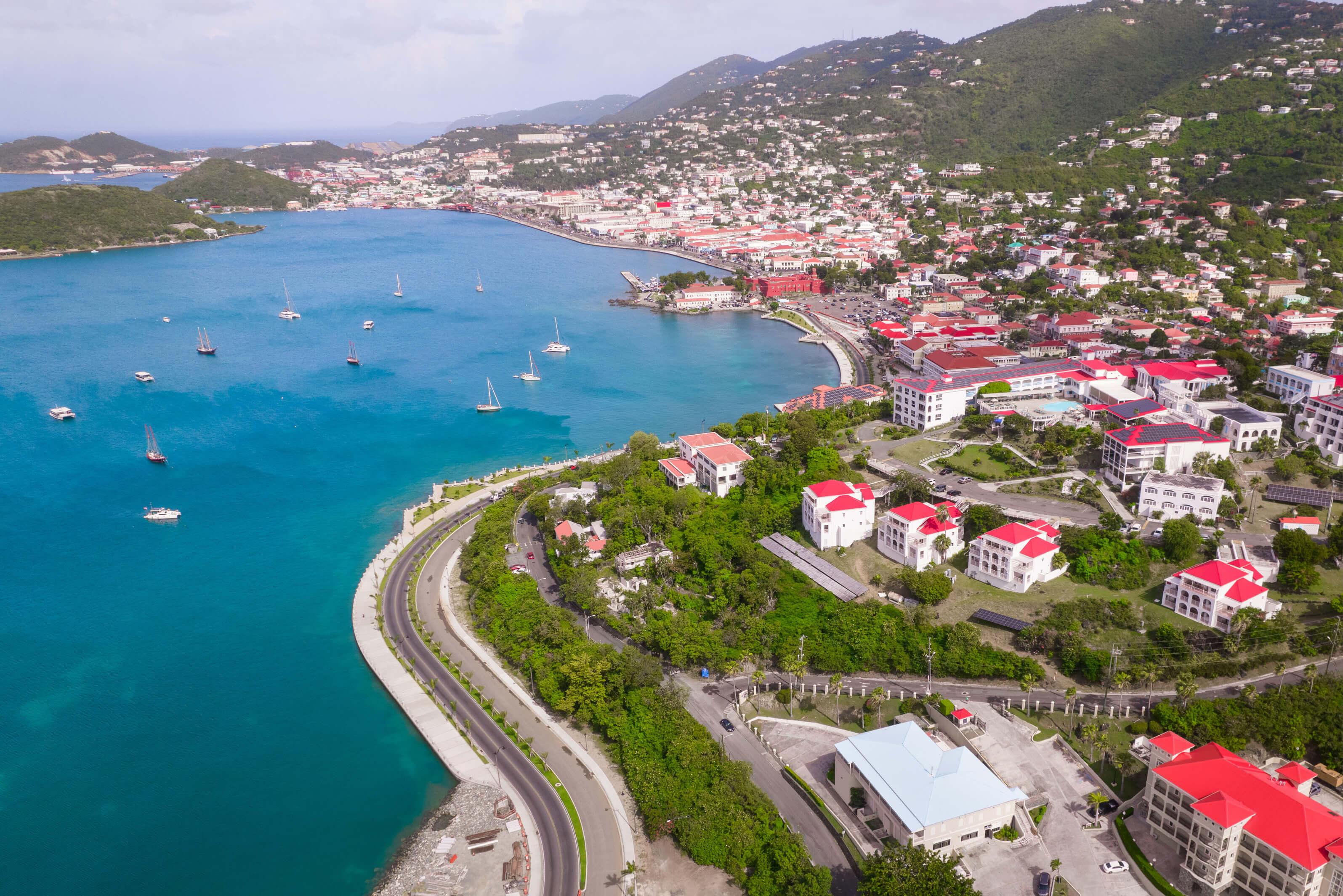 Coastal community in St. Thomas with windy road against the deep blue sea with many boats