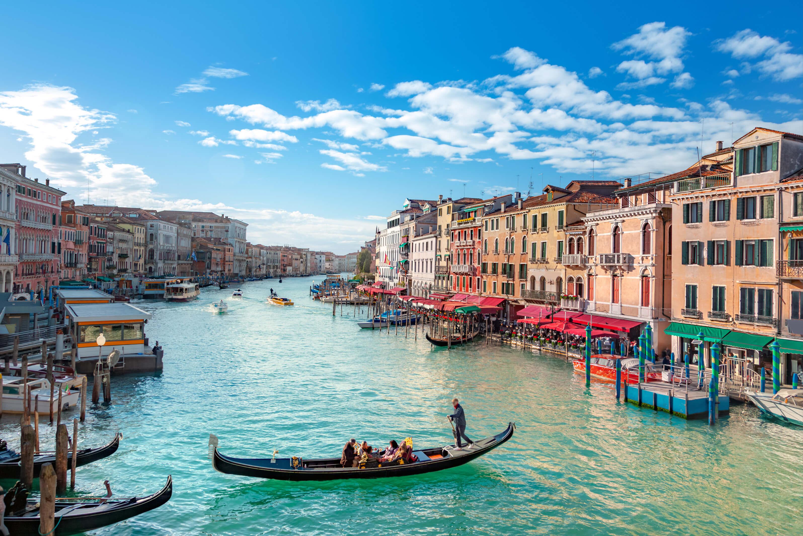 Canal in Venice, Italy filled with gondolas and boats, surrounded by charming and colorful architecture