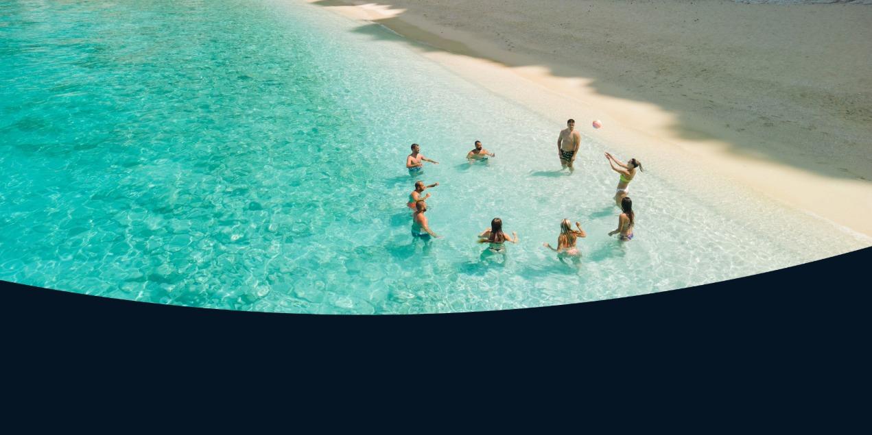 Group playing with a ball in shallow turquoise water near a sandy beach