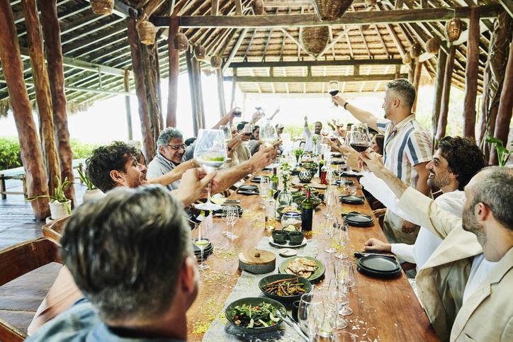 Group celebrating with food and drinks at outdoor destination wedding reception