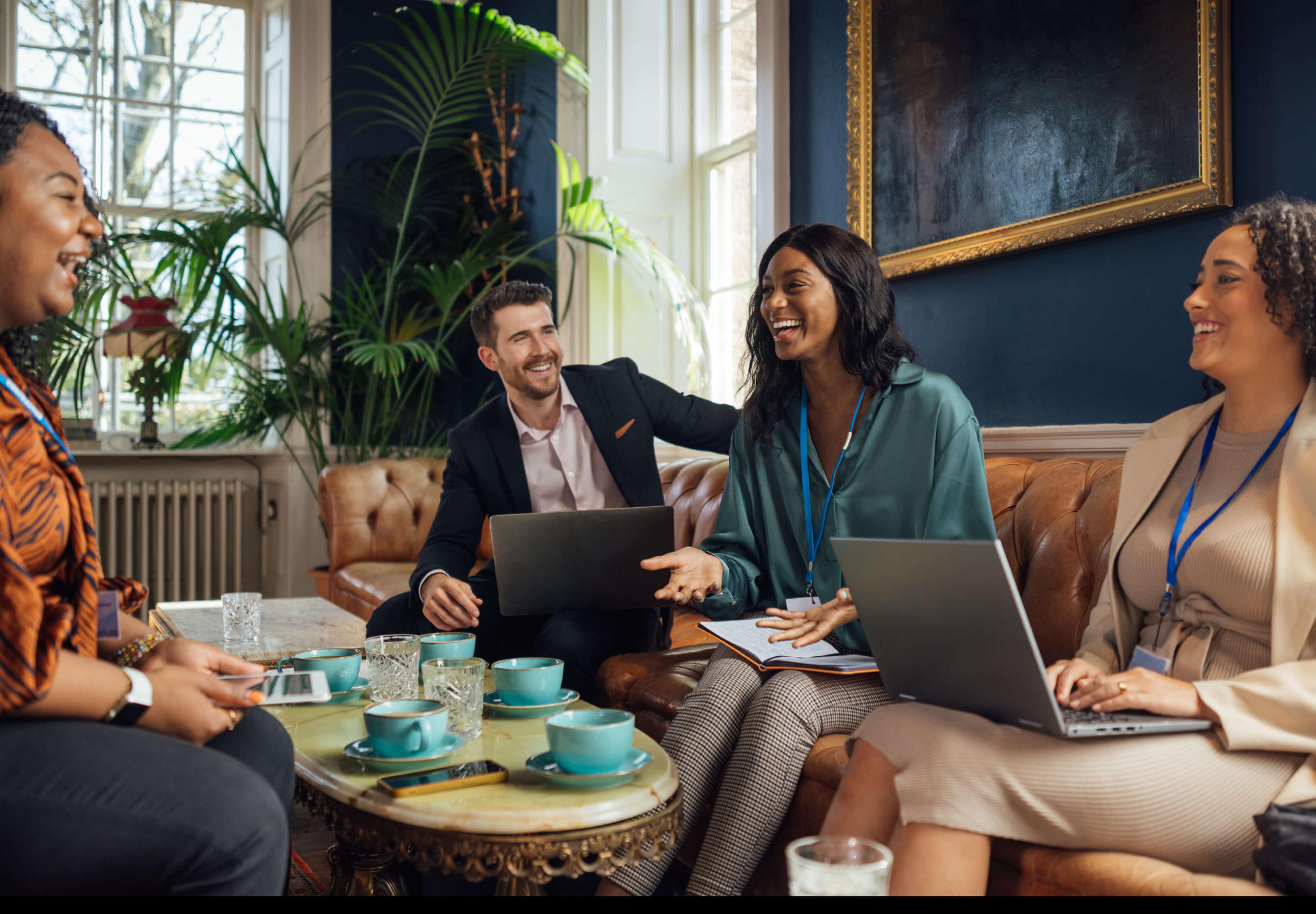 A group of coworkers smile while working from a hotel lobby