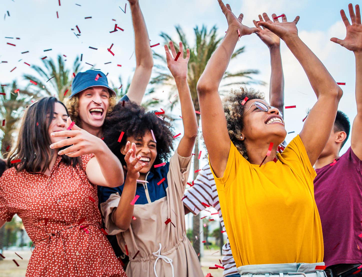 Coworkers celebrate with their arms in the air and smiles on their faces