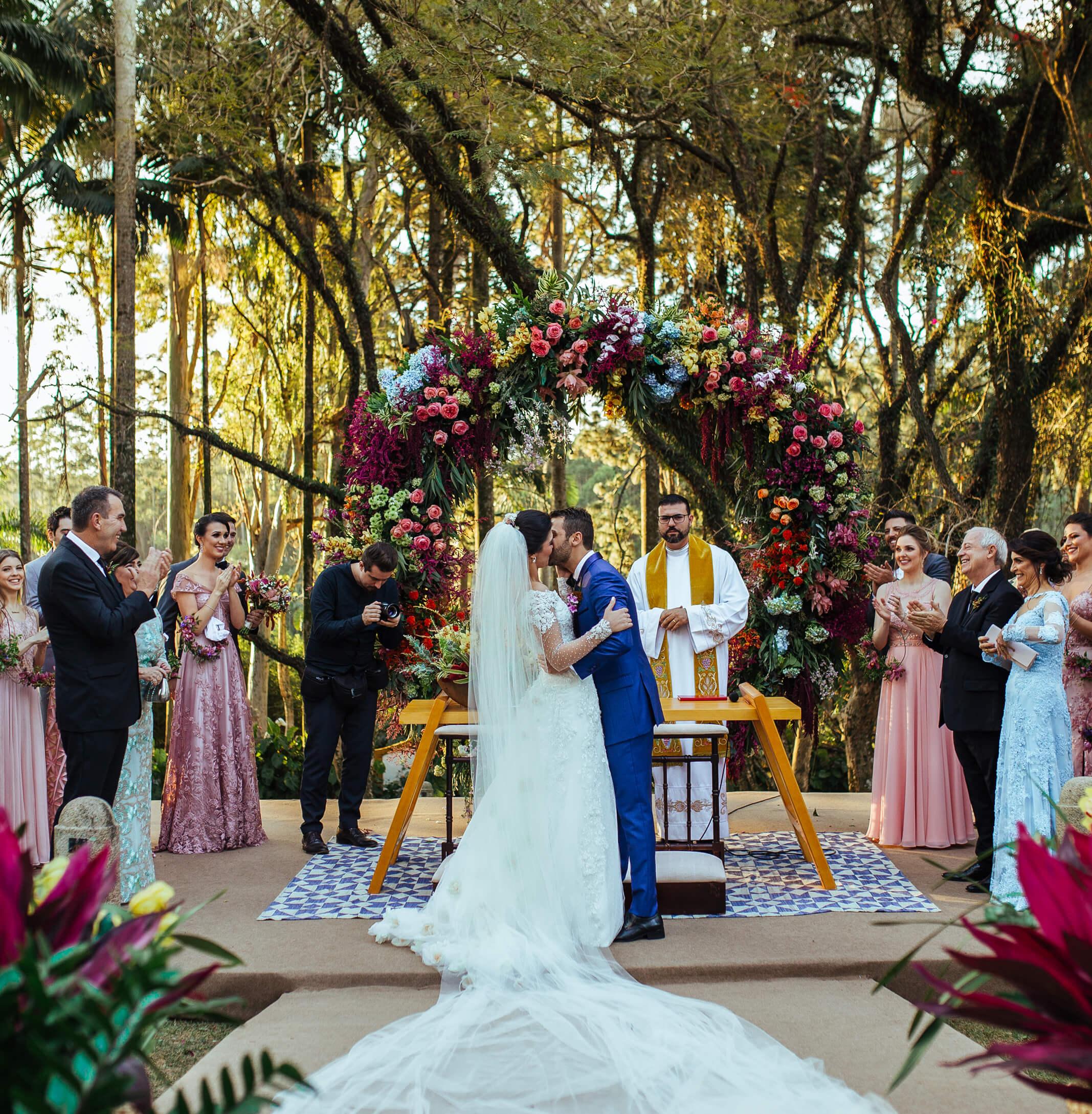 A couple shares their first kiss during their destination wedding in a forest environment